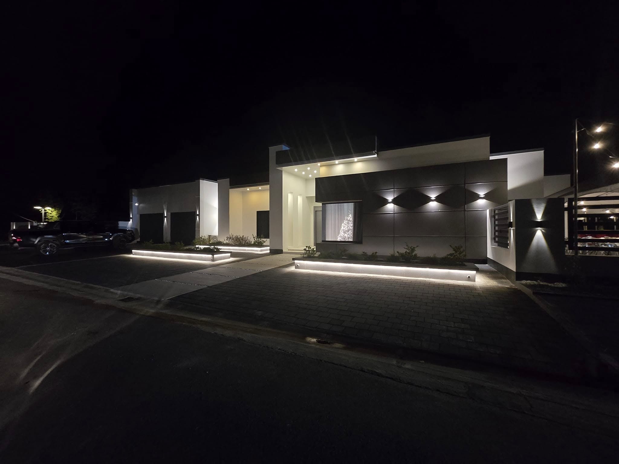 Completed house photographed at night with lit planters and facade panels.